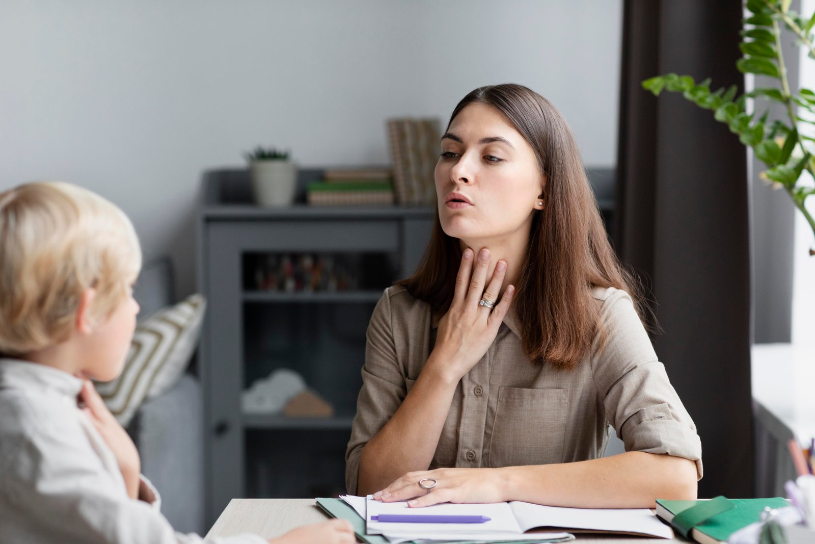young woman doing speech therapy with little boy